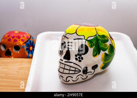 White Painted human skull with flowers for Mexico's Day of the Dead on color background, selected focus. Stock Photo