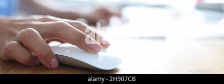 Female hand holding computer mouse and typing on computer keyboard closeup Stock Photo