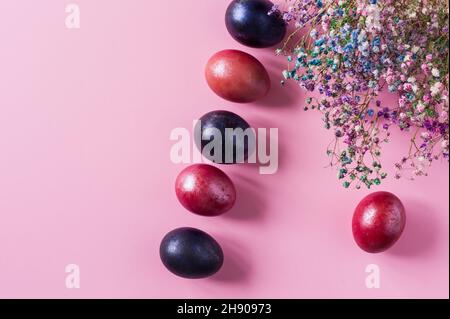 a view from above of the Easter colorful eggs and spring flowers laid out in a row. Mini Easter composition Stock Photo