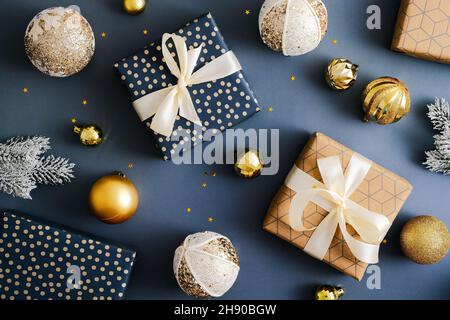 Christmas flatlay composition. Elegant gift boxes and golden baubles on dark blue table. Flat lay, top view, overhead. Vintage style. Stock Photo