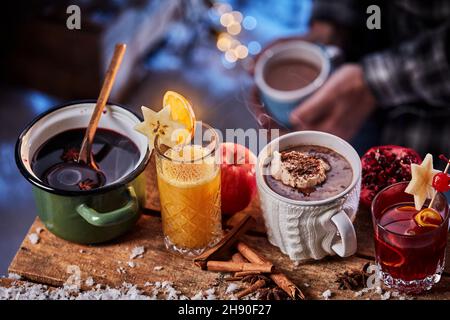 From above of set of various delicious winter beverages like cocoa and ginger drink with mulled wine on wooden table with snow and spices Stock Photo
