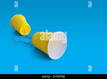 Comunication Yellow Plastic cup with string isolated on blue background Stock Photo