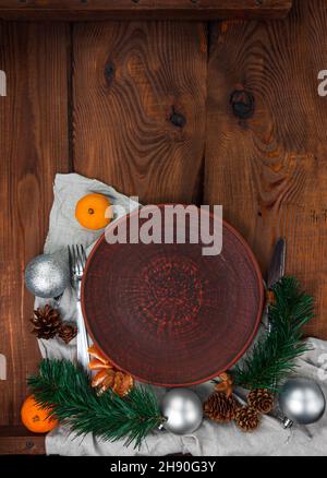 Christmas menu table setting empty clay plate fir tree tangerines festive event decoration linen tablecloth tableware Stock Photo