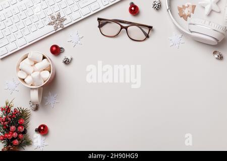 Winter desktop. New Year Christmas composition. Keyboard glasses gift marshmallow headphones on the gray table. Flat lay top view Stock Photo