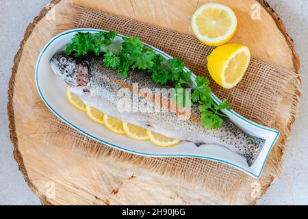 Fresh raw rainbow trout garnished with lemon slices and parsely - overhead view Stock Photo