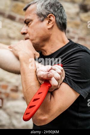 Knife disarm demonstration. Kapap instructor practice martial arts self defense knife threat disarming technique. Weapon retention and disarm training Stock Photo