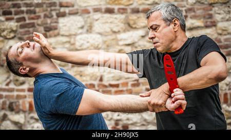 Knife disarm demonstration. Kapap instructor practice martial arts self defense knife threat disarming technique. Weapon retention and disarm training Stock Photo