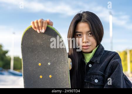 Stylish cool teen female skateboarder at skate park.