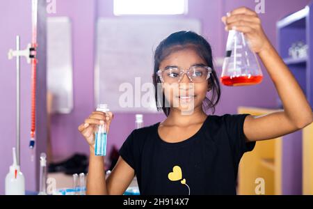 concentrated kid mixing chemicals in Florence flask while making experiment at chemistry laboratory - concept of education, knowledge and focused Stock Photo