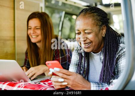Diverse traveling women working remotely in camper Stock Photo