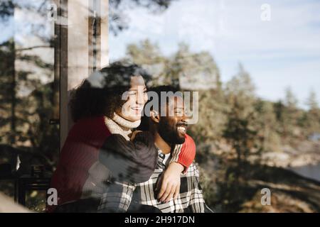 Smiling couple looking away seen through window Stock Photo