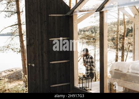 Mid adult man walking by cottage in forest Stock Photo
