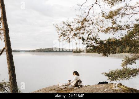 Young woman sitting on rock at lakeshore Stock Photo