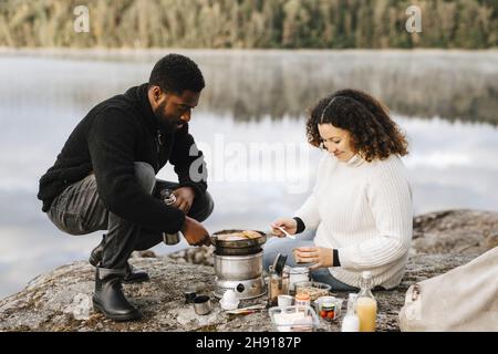 Young woman preparing food with boyfriend at lakeshore Stock Photo
