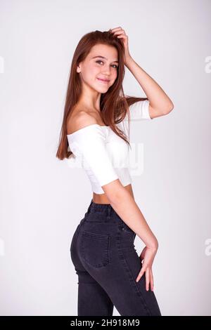 Close up portrait of a young beautiful brunette model in black jeans, isolated on white background Stock Photo