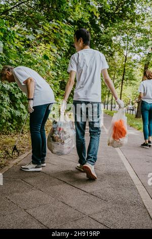 Male and female volunteers cleaning plastics on footpath Stock Photo