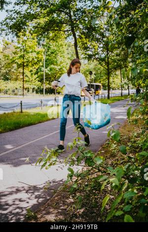 Young female volunteer cleaning plastic waste in park Stock Photo