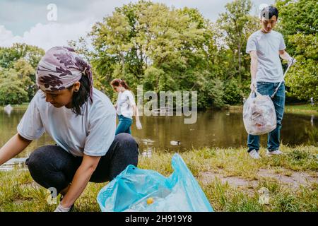 Male and female volunteers cleaning plastics near pond Stock Photo