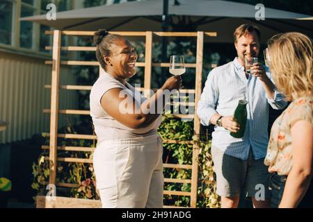Happy male and female friends enjoying dinner party at backyard Stock Photo