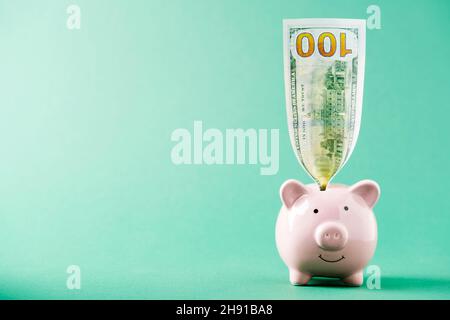 America dollars banknotes money into piggy bank on green background.  Stock Photo
