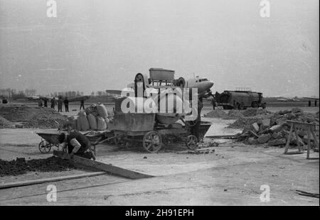 Warszawa, 1947-04-26. Odbudowa ze zniszczeñ wojennych lotniska cywilnego na Okêciu. Nz. robotnicy przy betoniarce. W tle samolot Lisunow Li-2. wb  PAP      Warsaw, April 26, 1947. Rebuilding the Okecie civilian airport from war damage. Pictured: workers at a concrete mixer. In the background the Lisunow Li-2 plane.  wb  PAP Stock Photo