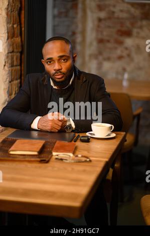 African-American man is working at a laptop in a cafe. Free work schedule, freelancer Stock Photo
