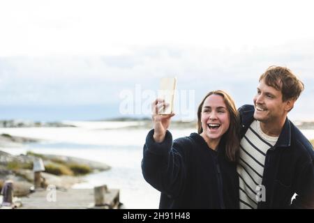 Happy heterosexual couple taking selfie through smart phone during vacation Stock Photo