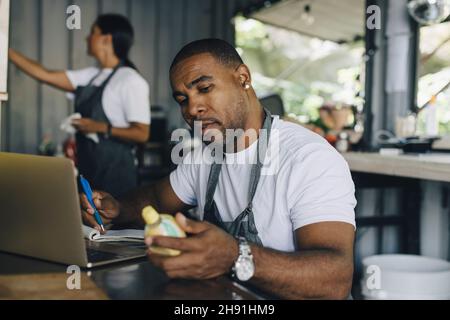 Male seller calculating bill while looking at product in food truck Stock Photo