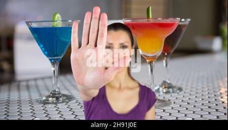 Digital composite image of woman showing stop hand sign against cocktail drinks on table Stock Photo