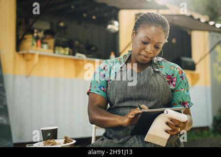 Young female entrepreneur using digital tablet against food truck Stock Photo