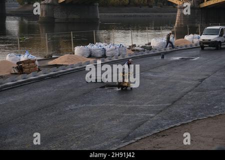 Budapest, Hungary - 1 November 2021: Worker in uniform paving asphalt using machinery on the embankment, Illustrative Editorial. Stock Photo