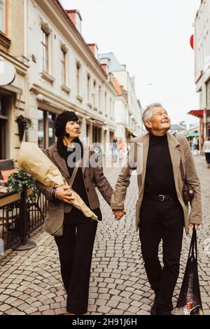 Senior couple holding hands while exploring city during vacation Stock Photo