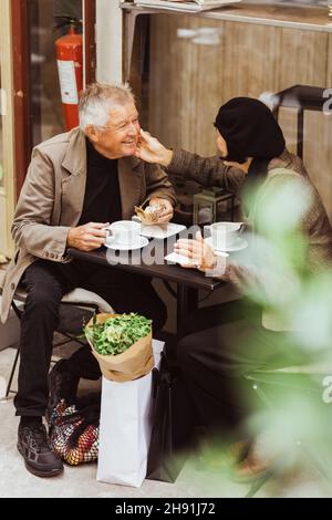 Elderly couple talking while having breakfast at sidewalk cafe Stock Photo