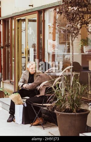 Senior man and woman sitting at sidewalk cafe in city Stock Photo