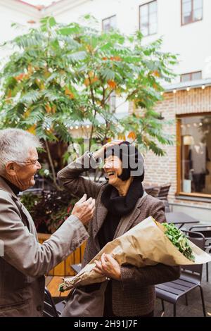 Cheerful senior couple talking while standing at sidewalk cafe in city Stock Photo