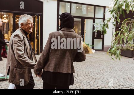 Happy senior man talking with woman while walking on street in city Stock Photo