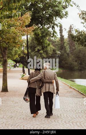 Rear view of senior couple walking on footpath in park Stock Photo