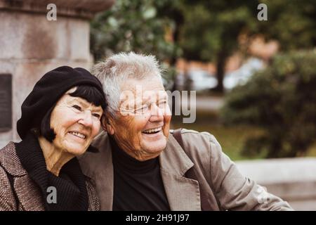 Cheerful senior couple looking away while sitting in park Stock Photo