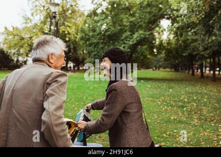 Happy elderly couple spending leisure time with electric bicycle in park Stock Photo