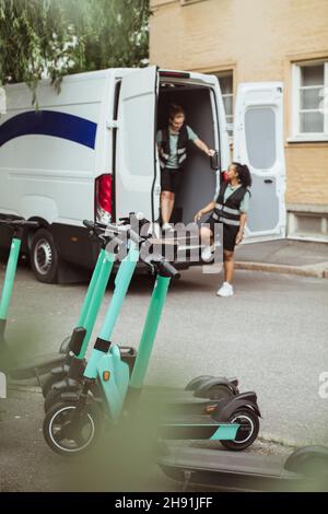 Young delivery woman in van talking with female coworker Stock Photo