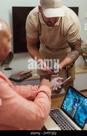 Male customer and maintenance engineer using smart phones in living room Stock Photo