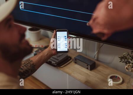 Male maintenance engineer showing app on smart phone to customer at home Stock Photo