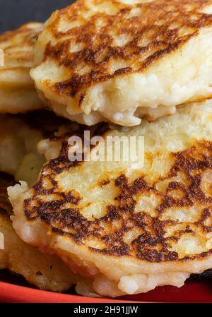 The Cheese pancakes from pot cheese lies in red plate.Photography on dark background close-up Stock Photo