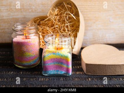 Children made fun colorful layered wax powder candles in home by pouring powder in old baby food jar and inserting wick inside. Hobby concept. Stock Photo