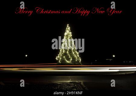 Merry Christmas ans Happy New Year post card, Christmas tree in the Park, Decorated with lights and light trails around
