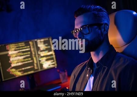 Profile photo of serious confident guy sitting chair operating database security evening loft business center Stock Photo