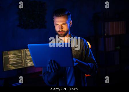 Portrait of clever intelligent skilled person hold netbook testing algorithms dark space business center Stock Photo