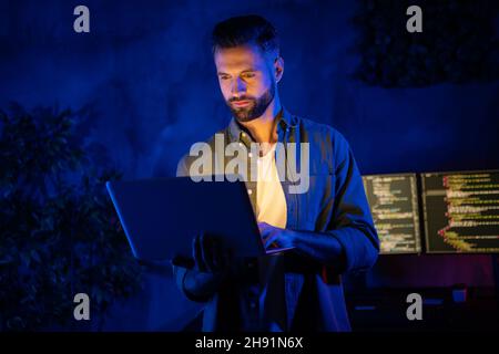 Photo of calm focused smart person hold netbook write email research information dark office room Stock Photo