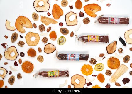 Above view of fruit and berries lozenge different colors in beautiful packaging and almonds, orange, apricot, raisins, walnuts, apples on white background. Concept of Natural and useful product.  Stock Photo
