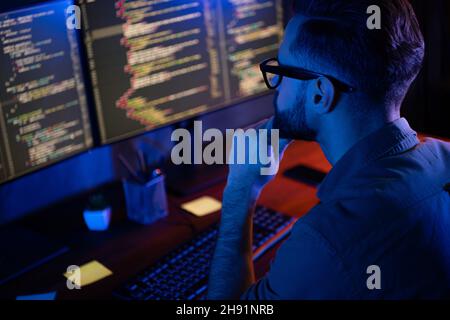 Profile portrait of intelligent minded person hand on chin look two monitors debugging database house loft space Stock Photo